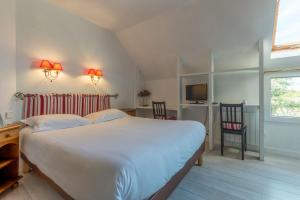 a bedroom with a bed and a desk and a television at Hotel Le Clos Fleuri in Le Palais