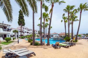 a resort with palm trees and a swimming pool at Siesta Mar Originals in Cala'n Porter