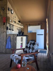 een keuken met een bank, een koelkast en een tafel bij De Hazelaarshof Luxe glampingtent bij natuurgebied De Millingerwaard in Kekerdom