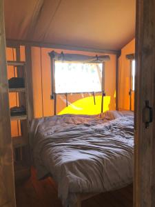 een slaapkamer met een bed voor een raam bij De Hazelaarshof Luxe glampingtent bij natuurgebied De Millingerwaard in Kekerdom