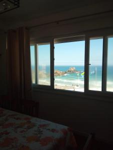 a bedroom with a window view of a beach at Apartamento Sto Estevão in Zambujeira do Mar +3 photos