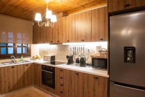 a kitchen with wooden cabinets and a stainless steel refrigerator at Dandy Villas Tsagkarada-Green Apple-Jacuzzi-Sea View in Tsagarada