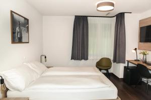 a hotel room with a white bed and a desk at Dihei - Hotel, Lounge, Bar in Dübendorf