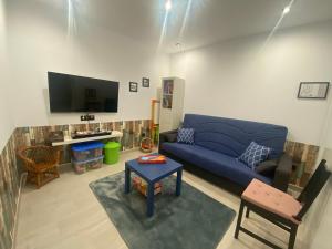 uma sala de estar com um sofá azul e uma televisão em Casa Rural La Alborá em Galisteo