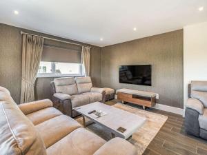 uma sala de estar com um sofá e cadeiras e uma televisão em Haven Cottage em Blackburn