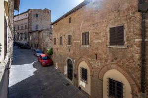 un callejón con un coche rojo estacionado junto a un edificio de ladrillo en Palazzo del Mercante en Montepulciano