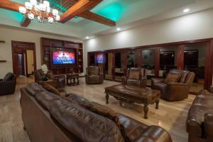 a large living room with leather furniture and a flat screen tv at Casa Amarillo Jaco Beach Costa Rica in Jacó