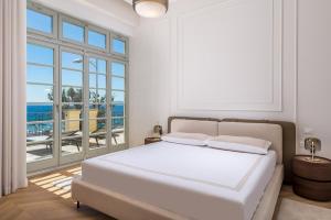 a white bedroom with a bed and a large window at Plaza Apartments in Opatija