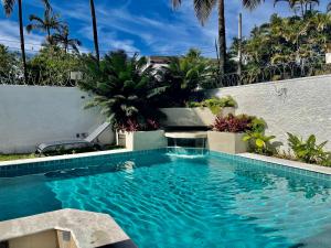 a swimming pool with blue water in a yard at Vila linda com SPA e Piscina a 50 metros da Praia in Guarujá