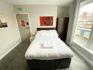 um quarto com uma grande cama branca e uma janela em OYO Studiotel Hartlepool em Hartlepool