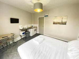 1 dormitorio con 1 cama blanca grande y escritorio en OYO Studiotel Hartlepool, en Hartlepool