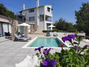 a swimming pool with purple flowers in front of a house at Ionian Juliet Villas in Kothoníkion