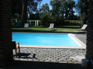 a swimming pool with two chairs and a table at Gîte Du Haut Ballot in Wambrechies