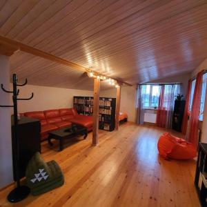 a living room with a red couch and wooden floors at Studio apartment and FREE airport transfer in Riga