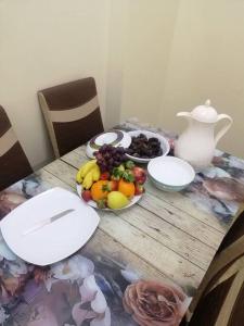 a table with bowls of fruit and a vase on it at فندق الرستاق in Ţakham