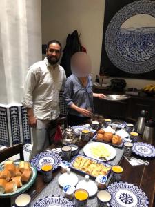 een man en een vrouw die naast een tafel met eten staan bij Dar Chez Khadija in Fès