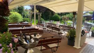 une terrasse avec des tables et des bancs en bois et un parasol dans l'établissement Meyers Gasthof, à Bothel