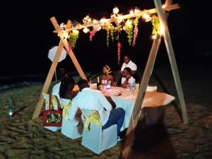 a group of people sitting at a table on the beach at Coconut Grove Beach Resort in Elmina