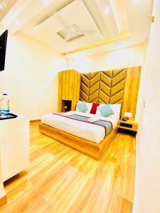 a bedroom with a large bed with a wooden headboard at Avista Hotel in Amritsar