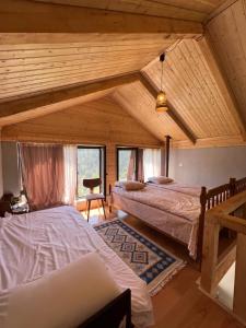 a bedroom with two beds in a room with wooden ceilings at Mitarbi Silence - cozy holiday cottages in mountains in Borjomi
