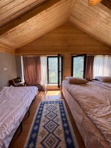 two beds in a room with wooden ceilings and windows at Mitarbi Silence - cozy holiday cottages in mountains in Borjomi