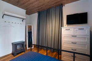 a bedroom with a bed and a dresser with a television at Семеен хотел и ресторант Райски залив in Golyama Zhelyazna