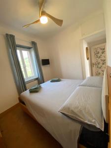 a bedroom with a white bed with a ceiling fan at Appartamento Victoria in Camogli