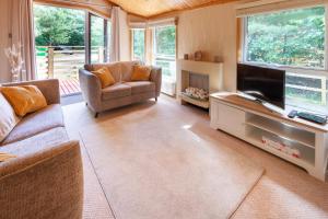a living room with a couch and a television at Hazel Lodge - Norfolk Cottage Agency in Weybourne