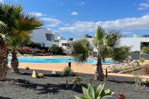 un complejo con piscina y palmeras en Suite Dreams Fuerteventura, en Villaverde