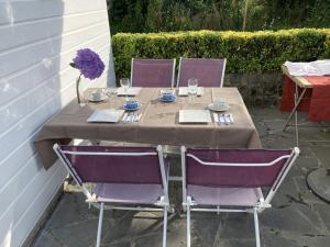 a table with three purple chairs and a table with glasses at LE CHALET de LA LONGERE in Beuvry-Nord