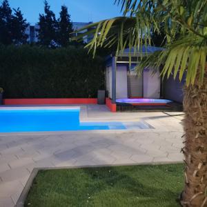 a swimming pool in front of a house with a palm tree at Résidence Les Alizés ''JACCUZI SAUNA PISCINE en plein centre ville" in La Roche-sur-Yon