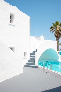 a white building with stairs and a swimming pool at White Cave Villas in Oia
