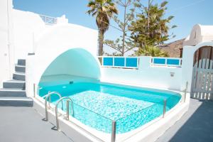 a swimming pool with a blue tub and blue chairs at White Cave Villas in Oia