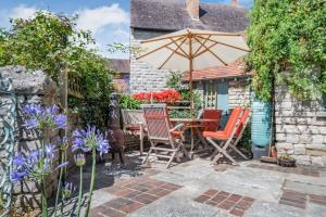 un patio con mesa, sillas y sombrilla en Passiflora Cottage, en Swanage