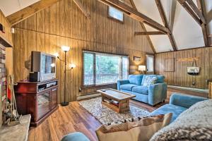 a living room with wooden walls and a blue couch and a tv at Game Room and Fire Pit Tree-Lined Pocono Lake Cabin in Pocono Lake