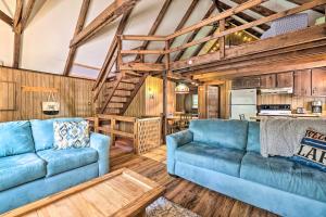 a living room with two blue couches and a kitchen at Game Room and Fire Pit Tree-Lined Pocono Lake Cabin in Pocono Lake