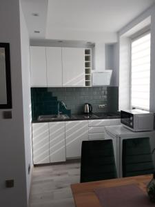 a kitchen with white cabinets and a sink and a microwave at Apartament do wynajęcia in Mikołajki