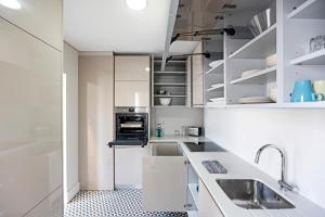 a white kitchen with white cabinets and a sink at Palácio das Cardosas Studio by LovelyStay in Porto
