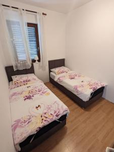 two twin beds in a room with a window at Apartments Magnolija 50m from beach in Srima