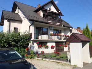 a white house with flowers on the balcony at Apartament Bronowice in Krakow
