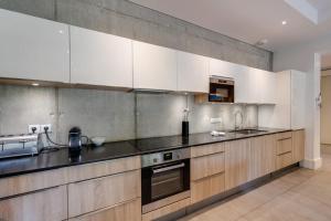 una cucina con armadietti bianchi e ripiani neri di Le Kube - Appartements de Prestige au centre d'Annecy ad Annecy