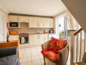 una cocina con armarios blancos y una silla con almohada roja en Sea Breeze en Weymouth
