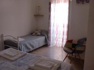 um quarto com uma cama, uma cadeira e uma janela em DMZ - Agrigento Apartment em Agrigento