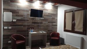a room with two chairs and a tv on a wall at Hotel Ristorante Caligiuri in Decollatura