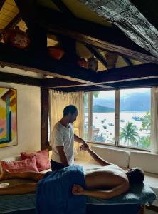 un homme préparant un homme à se coucher sur un lit dans l'établissement Pousada Vila do Mar, à Búzios