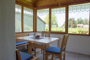 ein Esszimmer mit einem Tisch, Stühlen und Fenstern in der Unterkunft Ferienwohnung Kleiner Spatz in Leutkirch im Allgäu