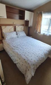 1 dormitorio con 1 cama con edredón blanco y ventana en A-Wave From It All, en Montrose