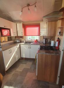 una pequeña cocina con armarios blancos y fregadero en A-Wave From It All, en Montrose