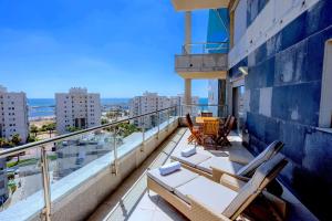Un balcón con sillas y mesas en un edificio en Luxury Marina 4BR apartment by Airsuite en Ashdod