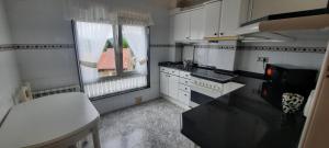 a kitchen with white cabinets and a sink and two windows at Apartamento Sopuente in Selaya